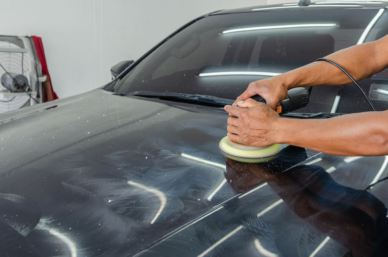 Home Close-up of a mechanic polishing a cars surface in an indoor auto workshop.
